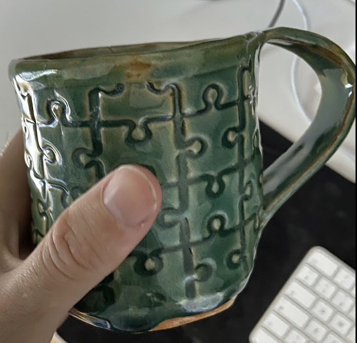 a green cup with a puzzle pattern on it.
